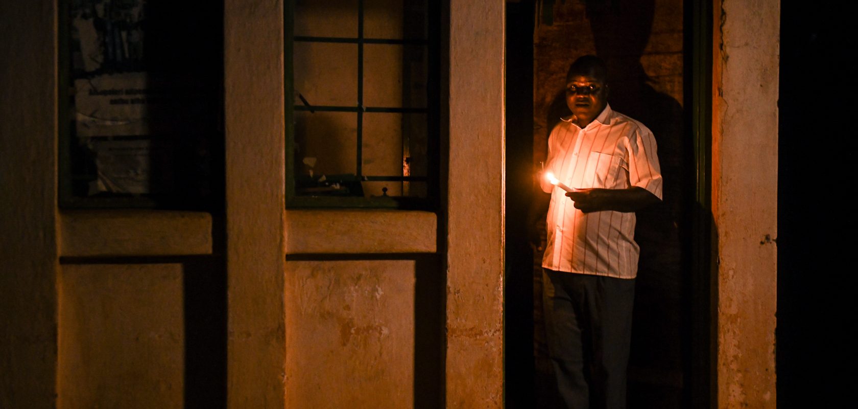 TA Kasakula holding a candle in a doorway.