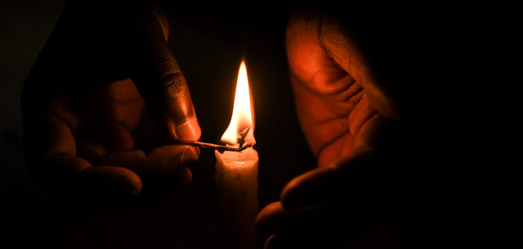 A candle is lit in the dark.