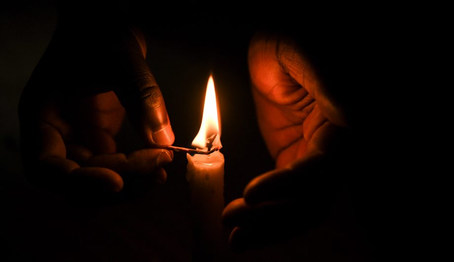 A candle is lit in the dark.