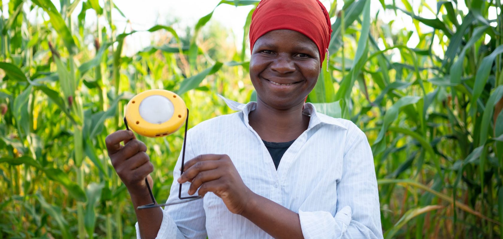 Liness hold her solar light proudly in her fields where she farms