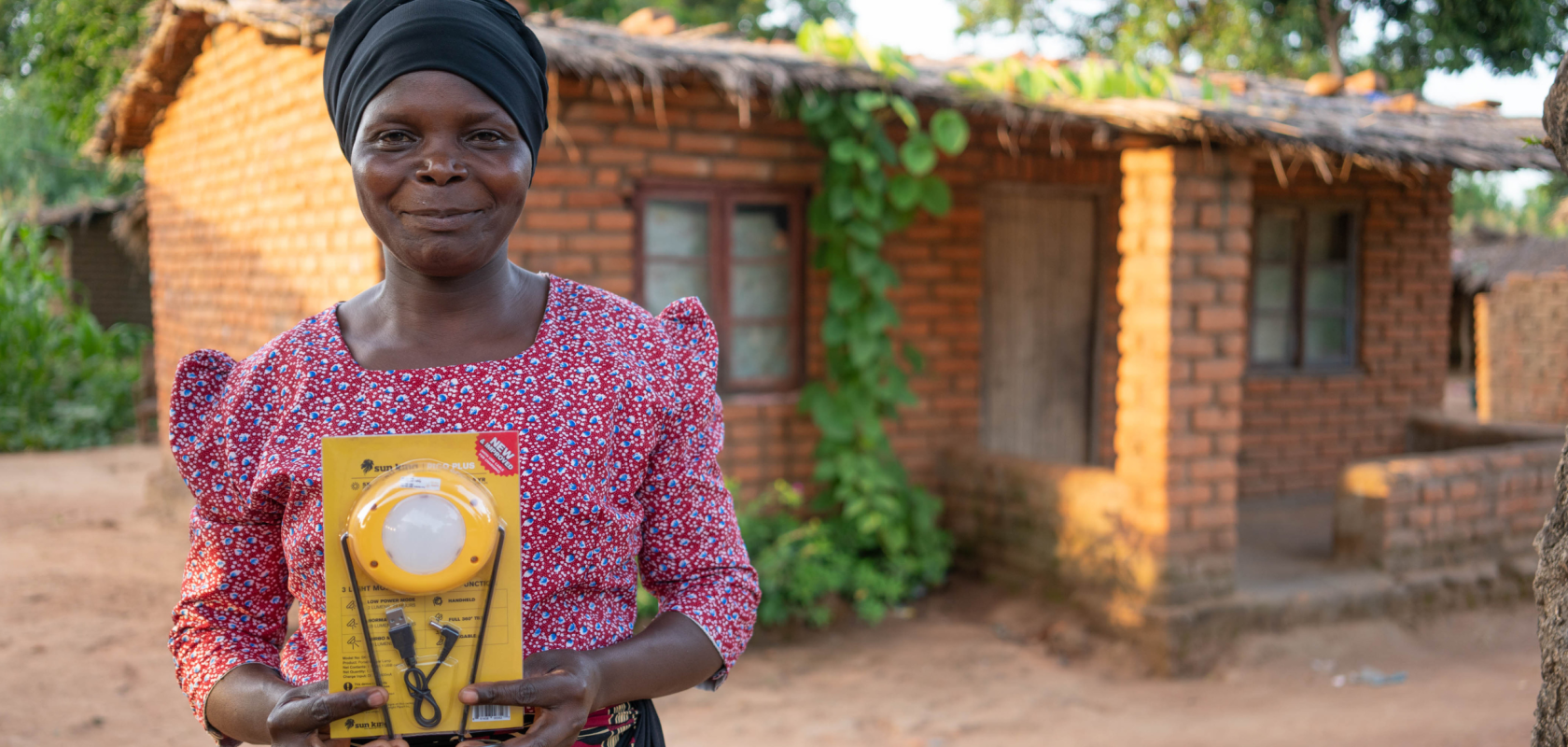 Eness is standing out the front of her house, holding a solar light, smiling