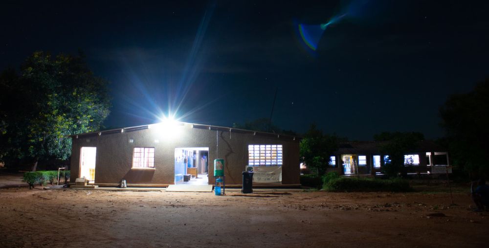 Hofmeyr Zonal Rural Health Centre in Nyimba District, Eastern Province, Zambia, brightly lit at night, showcasing reliable solar-powered lighting against a dark rural backdrop.