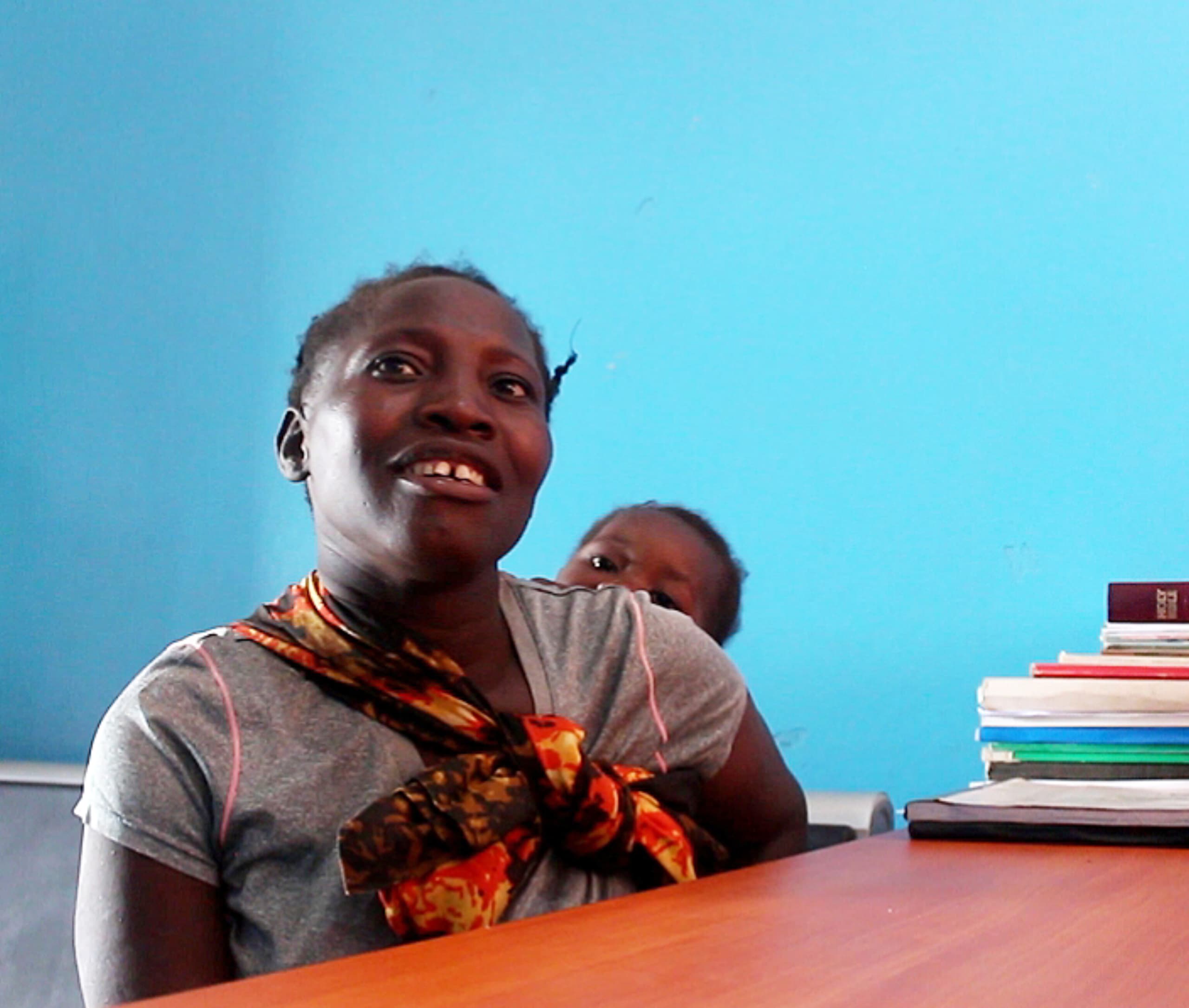 Lenia Tembo, a mother from Nyimba District, sits with her baby, recalling how reliable lighting transformed her childbirth experience.