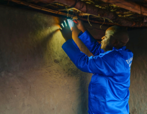 A technician installs a solar light on the ceiling of a rural home.